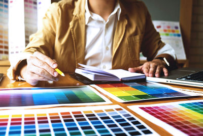 Midsection of man with color swatches sitting at desk