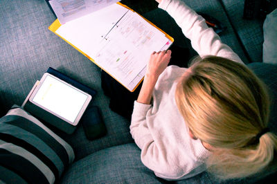 High angle view of woman using phone while sitting on table