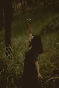 Rear view of woman standing in forest