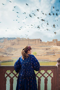 Woman standing by railing against buildings