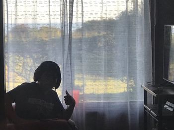 Man looking at camera while sitting in glass window