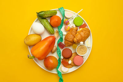 High angle view of fruits in plate against yellow background