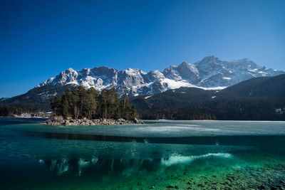 Scenic view of lake and mountains against clear blue sky