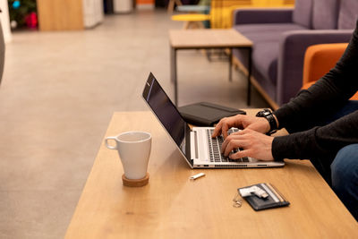 Midsection of man using laptop on table