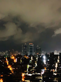 Illuminated buildings in city against sky at night