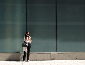 Full length of woman standing against wall