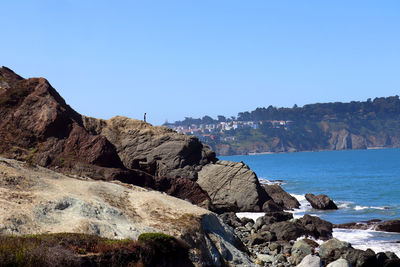 Rock formations on beach against clear blue sky