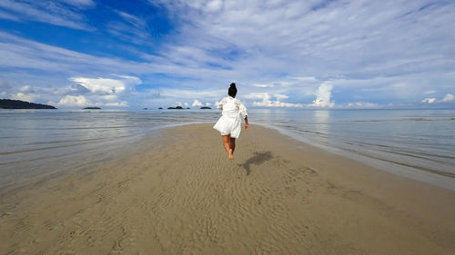 Rear view of woman on beach against sky