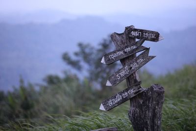 Close-up of text on wooden post against sky