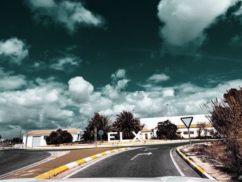 Road by trees against sky