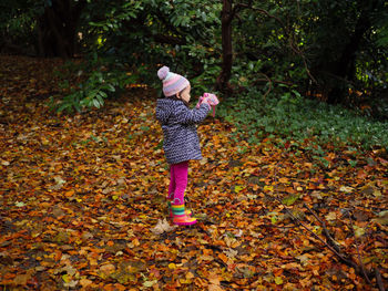 Girl standing on leaves during autumn taking photographs 