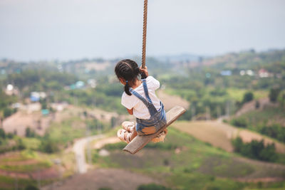 Rear view of boy on swing at playground