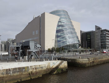 Buildings by river against sky in city