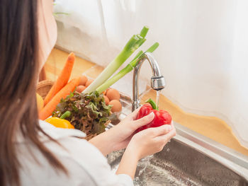 Midsection of woman holding ice cream at home