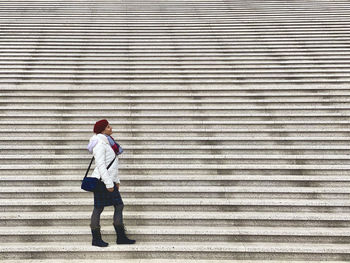 Full length of woman standing on wide stairs 