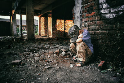 Rear view of people sitting on wall of building