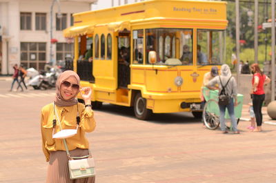 Portrait of young woman standing in city