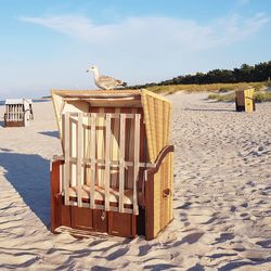 Hooded chairs on beach against sky