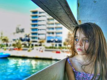 Thoughtful girl looking at sea through railing 