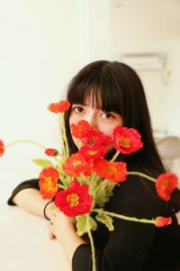 Portrait of woman holding red flowers