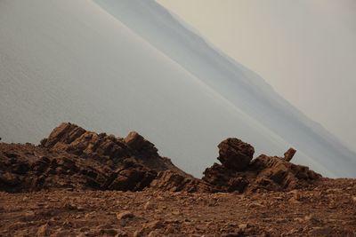 Rock formations in desert at the sea against sky