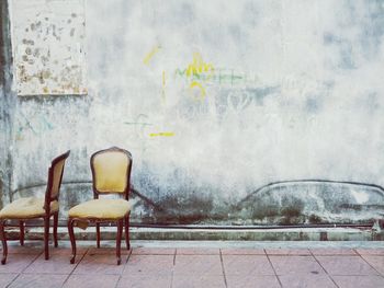 Pair of empty chair against weathered wall