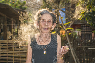Portrait of senior woman smoking weed at yard