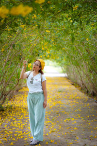 Woman wearing a yellow hat with yellow flowers in the forest