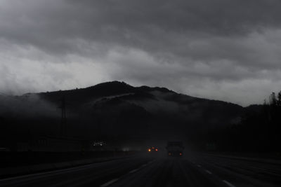 Road by mountain against sky at dusk