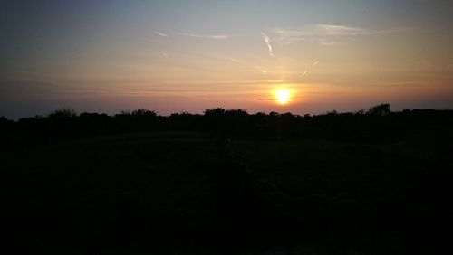 Scenic view of silhouette field against sky at sunset