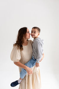 Side view of mother and daughter against white background