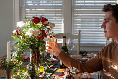 Midsection of woman holding flowers on table at home