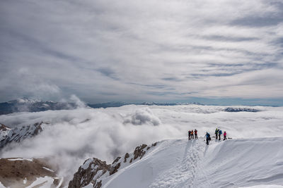 People skiing on snowcapped mountain against sky