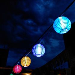 Low angle view of illuminated ferris wheel against cloudy sky