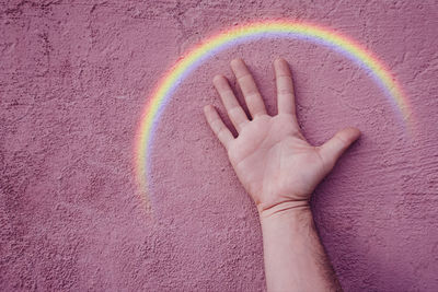 Hand with a rainbow on the pink wall. lgbt symbol