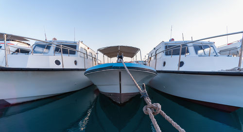 Sailboats moored at harbor against clear blue sky