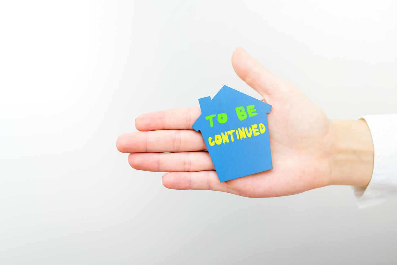 CLOSE-UP OF HAND HOLDING PAPER AGAINST WHITE BACKGROUND