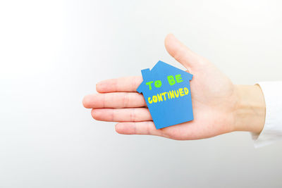 Close-up of hand holding paper over white background