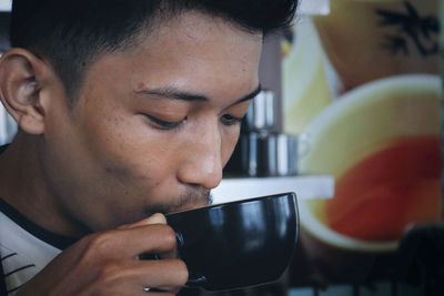 Close-up of young man having drink in cup