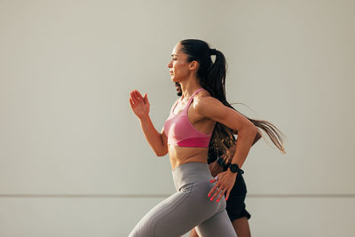 Full length of young woman exercising against wall