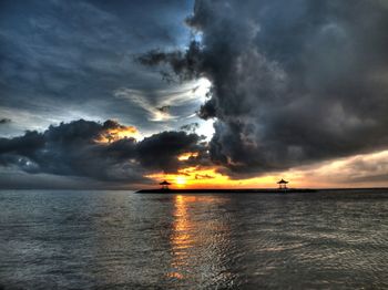 Scenic view of sea against cloudy sky at sunset