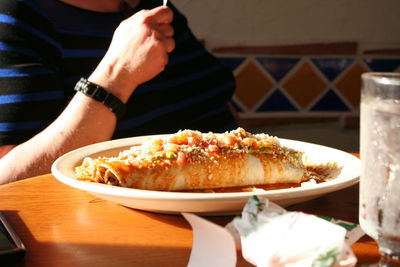 Midsection of man having burrito in restaurant