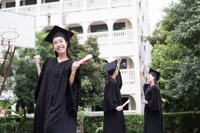 Cheerful student with clenched fist wearing graduation gown