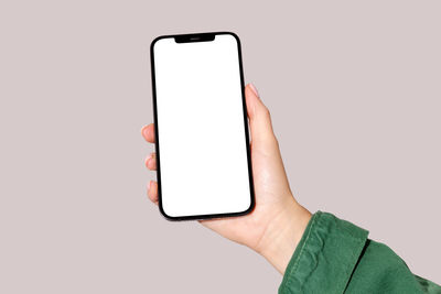 Cropped hand using mobile phone against white background