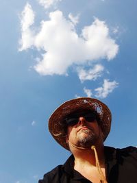 Low angle view of man wearing hat against sky