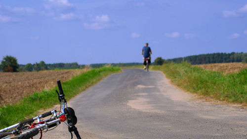 Rear view of man riding bicycle on road