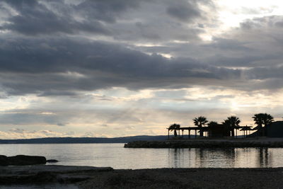 Silhouette people by sea against sky during sunset
