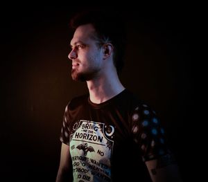 Close-up of young man looking away against black background