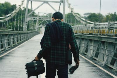 Rear view of man walking on footbridge