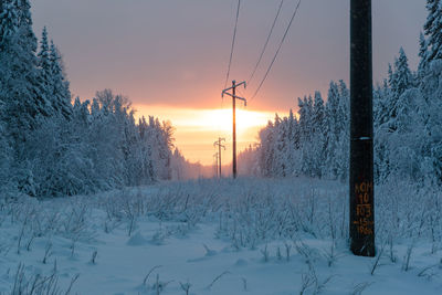 Snow covered field against sky during sunset